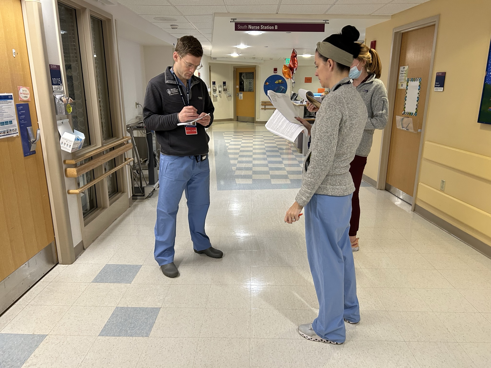Clinicians standing in hallway in group discussion