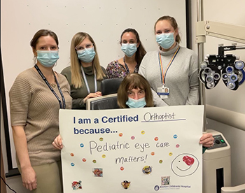 Orthoptists standing with a sign that says, "I am a certified Orthoptist because pediatric eye care matters!"