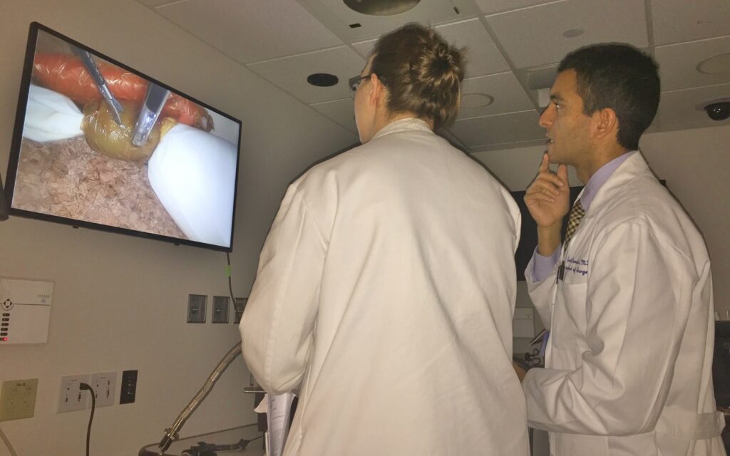 Doctors observing a surgical procedure on a TV
