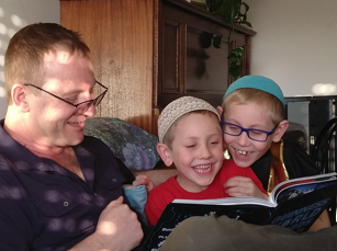 Dennis Rosen reading a book with two sons