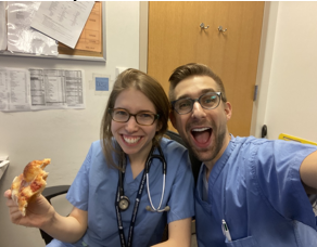 Elliot Rabinowitz smiling and eating pizza with Katie Krone