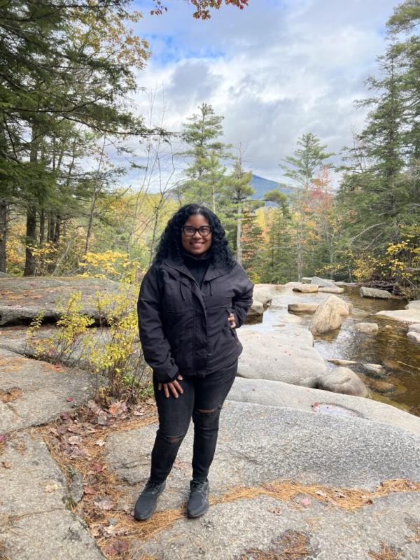 Genesis Michel in front of a river and fall foliage