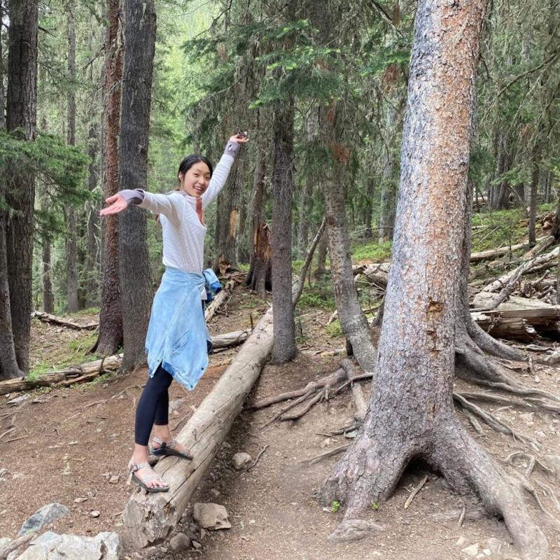 Joanne Kim balancing on a fallen log in the woods