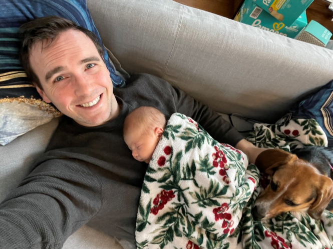 Taylor Baumann with a baby and dog sleeping on him
