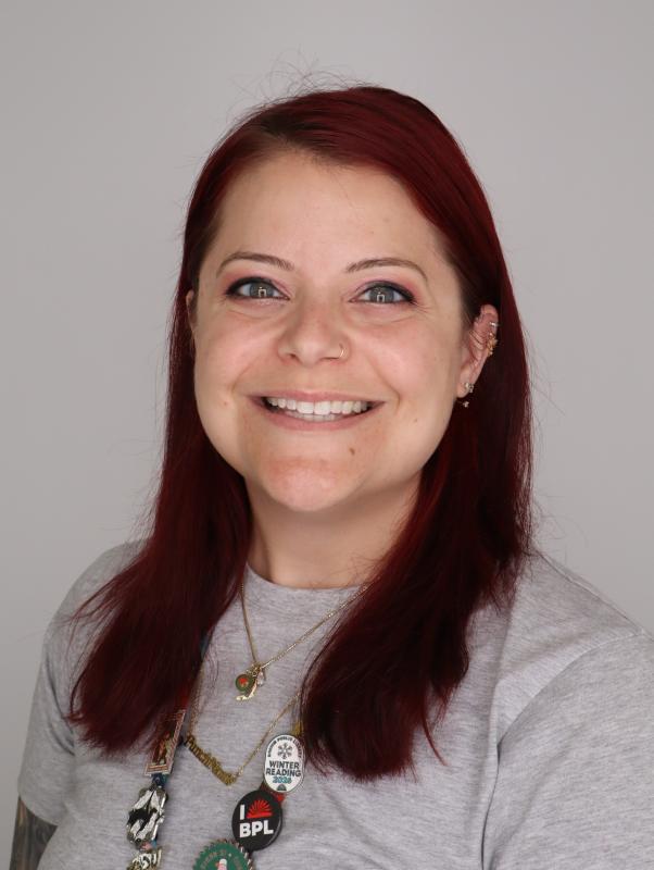 Headshot of Anna Boarini, a woman with red hair in front of a grey background.