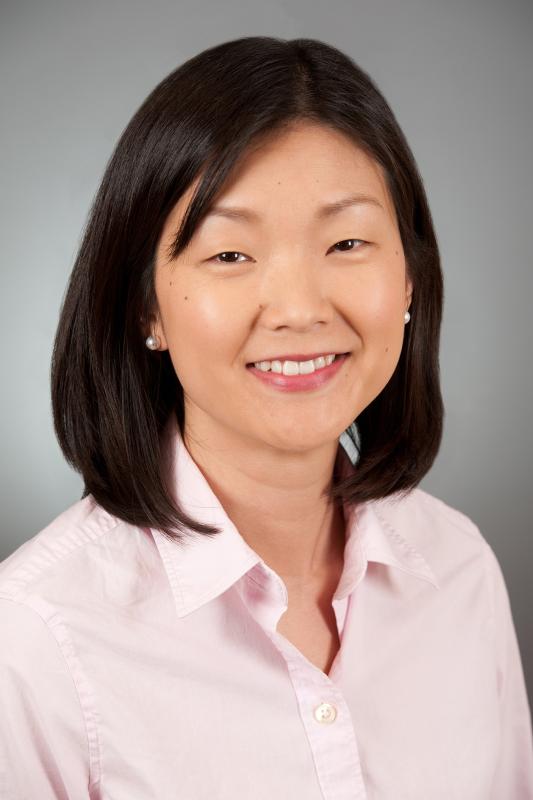 Headshot of Mindy Lo, a woman wearing a pink shirt in front of a grey background.